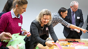 different people are standing around a table full of colourful paper