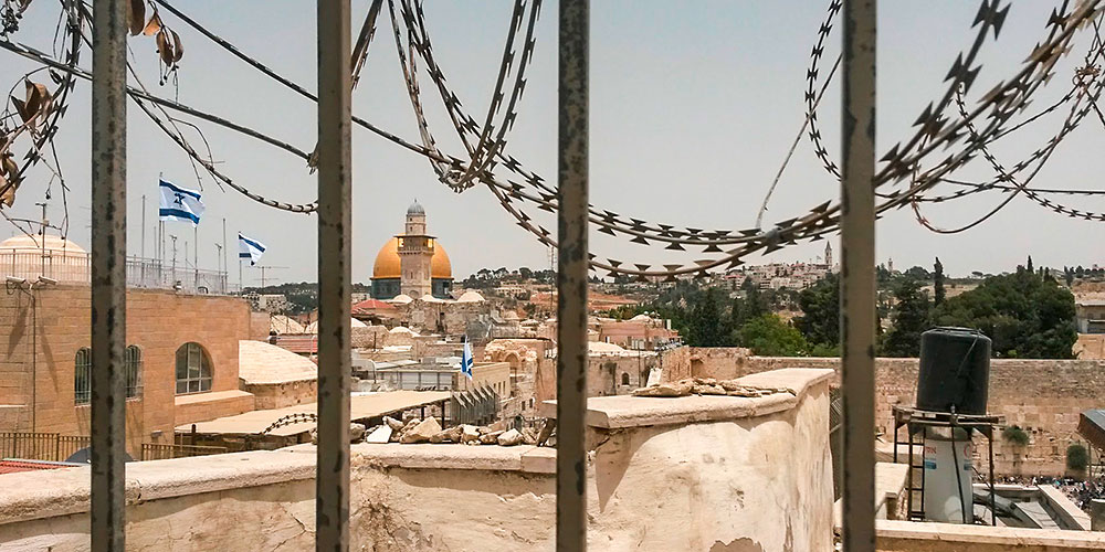 The Old City of Jerusalem seen through coils of razor wire.