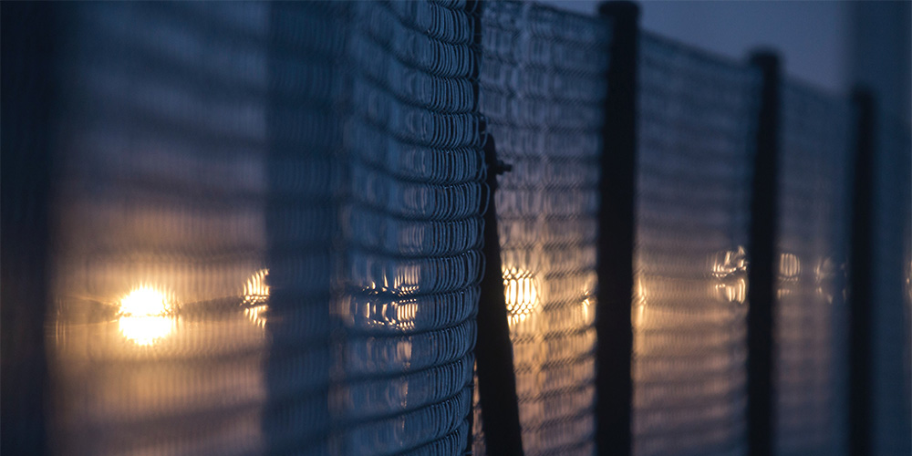 A high fence at night illuminated by spotlights