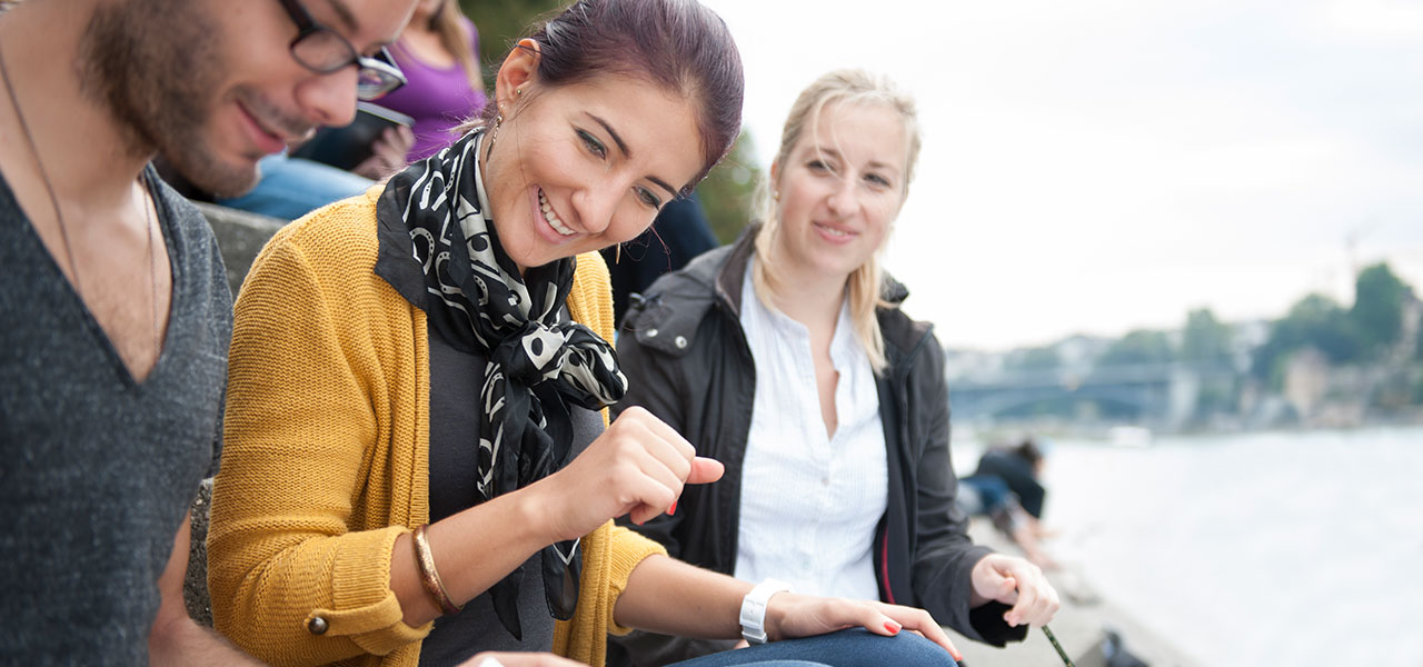 Junge Studierende sitzen am Rheinufer