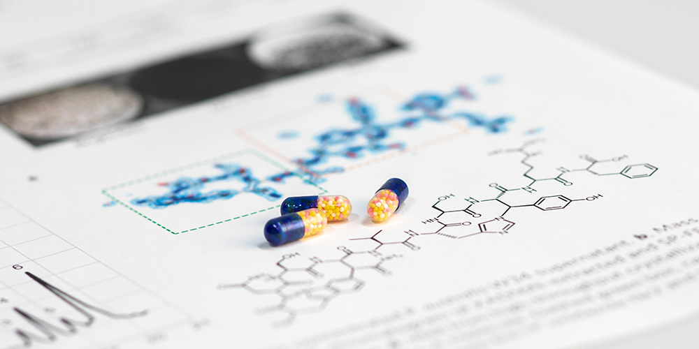 Pills on a book with chemical formula