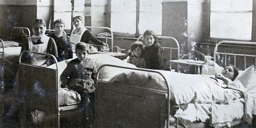Kinder in Spitalbetten mit Krankenschwestern.