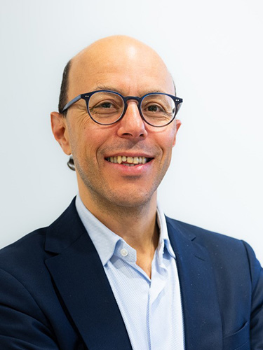 Prof. Dr. Mohamed Bentires-Alj in hellblauem Hemd und dunkelblaubem Kittel, mit Brille Prof. Dr. Mohamed Bentires-Alj in hellblauem Hemd und dunkelblaubem Kittel, mit Brille