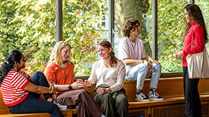 Fünf Studierende unterhalten sich und lachen im Flur des Kollegienhauses.