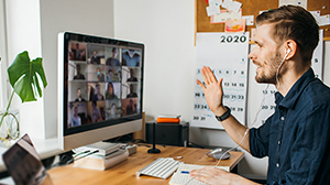 sitzende Person vor Bildschirm während in einem Onlinemeeting