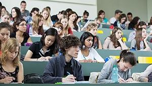 Hörsaal mit Studiernenden an der Universität Basel. Blick auf die Studierenden die aufmerksam und Notizen machend der Vorlesung beiwohnen.