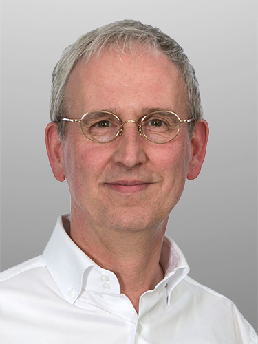Porträt eines älteren Mannes mit kurzen grauen Haaren, runder Brille und weißem Hemd vor einem einfarbigen grauen Hintergrund. Porträt eines älteren Mannes mit kurzen grauen Haaren, runder Brille und weißem Hemd vor einem einfarbigen grauen Hintergrund.
