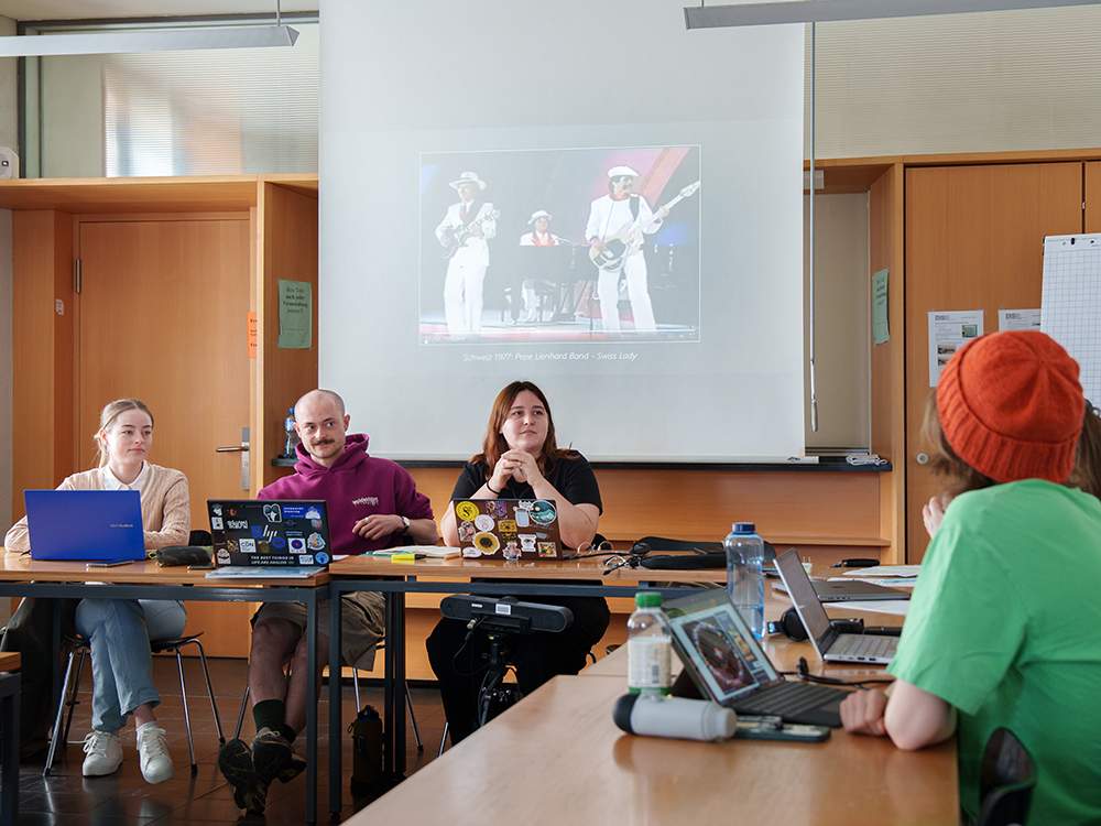 Die Germanistik-Studierenden Johanna Glowacki, Charles Thormann und Florence Remy halten ein Referat über die Inszenierung von nationaler Identität und Europeanness am ESC. Die Germanistik-Studierenden Johanna Glowacki, Charles Thormann und Florence Remy halten ein Referat über die Inszenierung von nationaler Identität und Europeanness am ESC.