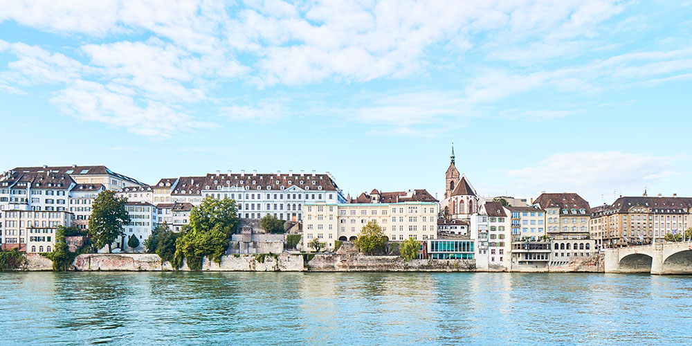 Blick über den Rhein auf die Alte Universität Basel an einem schönen Sommertag