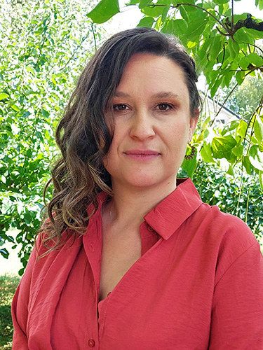 Frau mit braunen, welligen Haaren in einer rosaroten Bluse. Frau mit braunen, welligen Haaren in einer rosaroten Bluse.