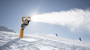 Schneekanone, welche eine bereits weisse Piste beschneit