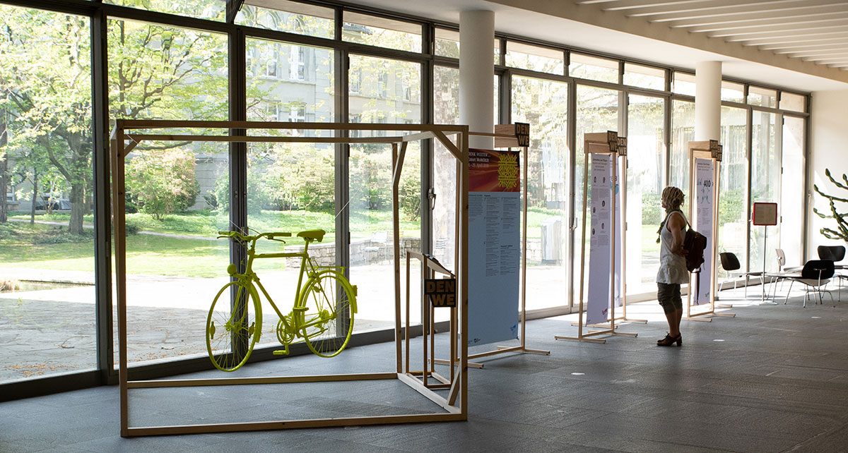 The picture shows a wooden cube in which a bicycle is suspended.
