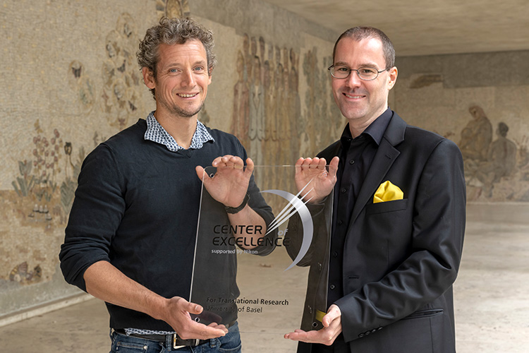 Michael Abanto and Pascal Lorentz hold a sign "Center of Excellence" Michael Abanto and Pascal Lorentz hold a sign "Center of Excellence"