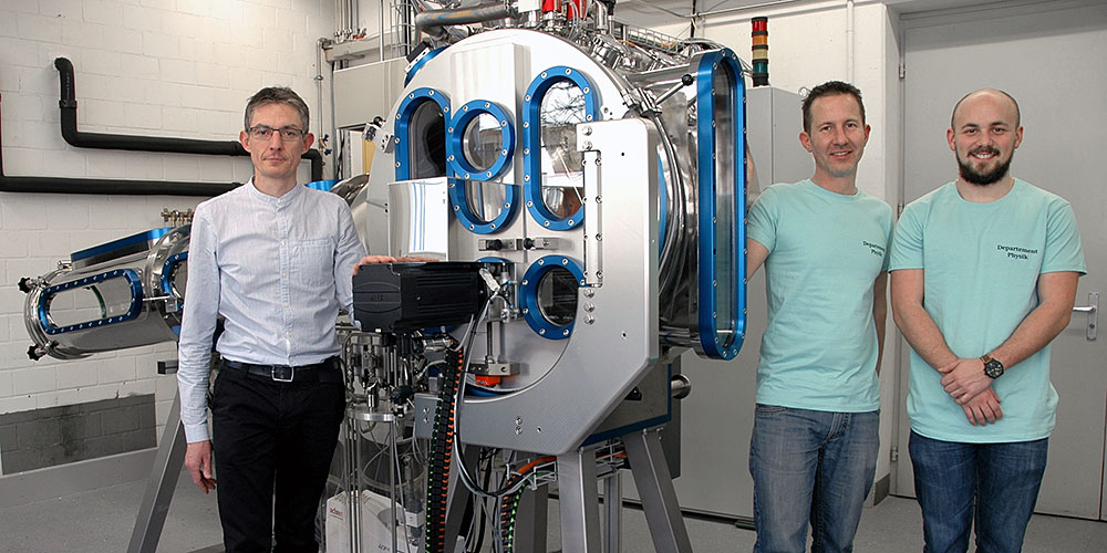 Dr. Laurent Marot und seine Mitarbeiter Silvester Jakob und Marco Martina neben der Anlage, in der metallische Gläser hergestellt werden. (Bild: HKBB)