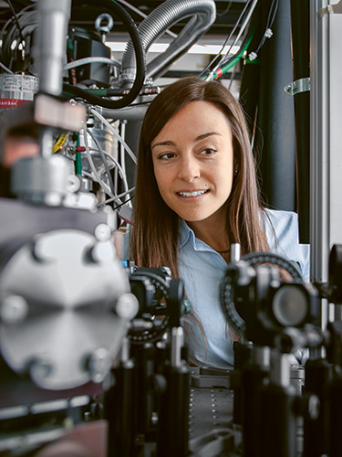 Young female researcher inspecting a complex instrument Young female researcher inspecting a complex instrument
