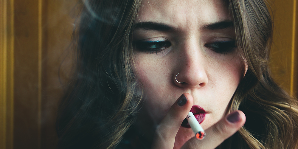 Junge Frau zieht an einer Zigarette. 