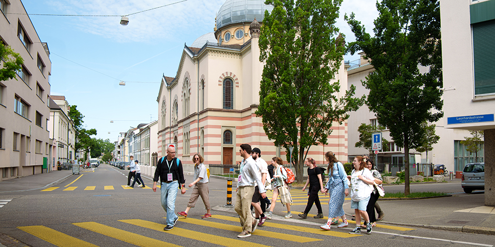 Prof. Dr. Erik Petry und eine Gruppe von Studierenden überqueren vor der Basler Synagoge die Strasse.