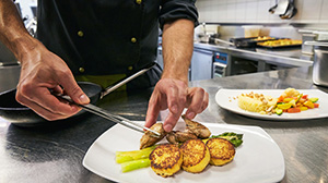 Cook preparing a menu in a SV Mensa of the University of Basel