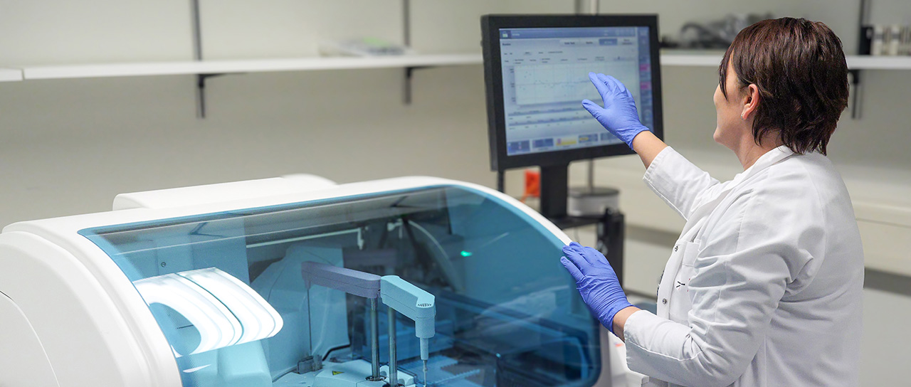 A laboratory specialist operates an automated system used to analyze blood samples.