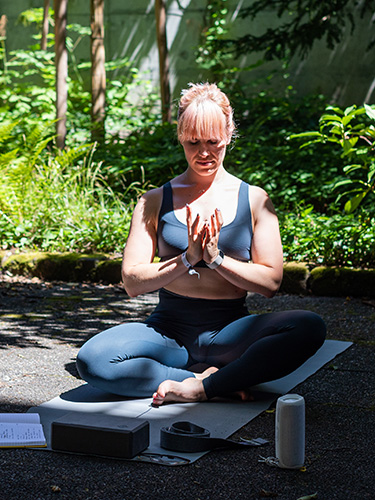 Nadine Felber sitzt im Schneidersitz auf der Yoga-Matte. Nadine Felber sitzt im Schneidersitz auf der Yoga-Matte.