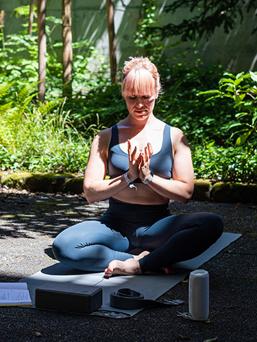 Nadine Felber is sitting cross-legged on the yoga mat.