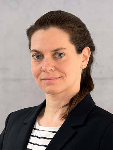 Porträt einer Frau mit zurückgebundenen dunklen Haaren, schwarzem Blazer und gestreiftem Oberteil vor hellem Hintergrund. Porträt einer Frau mit zurückgebundenen dunklen Haaren, schwarzem Blazer und gestreiftem Oberteil vor hellem Hintergrund.