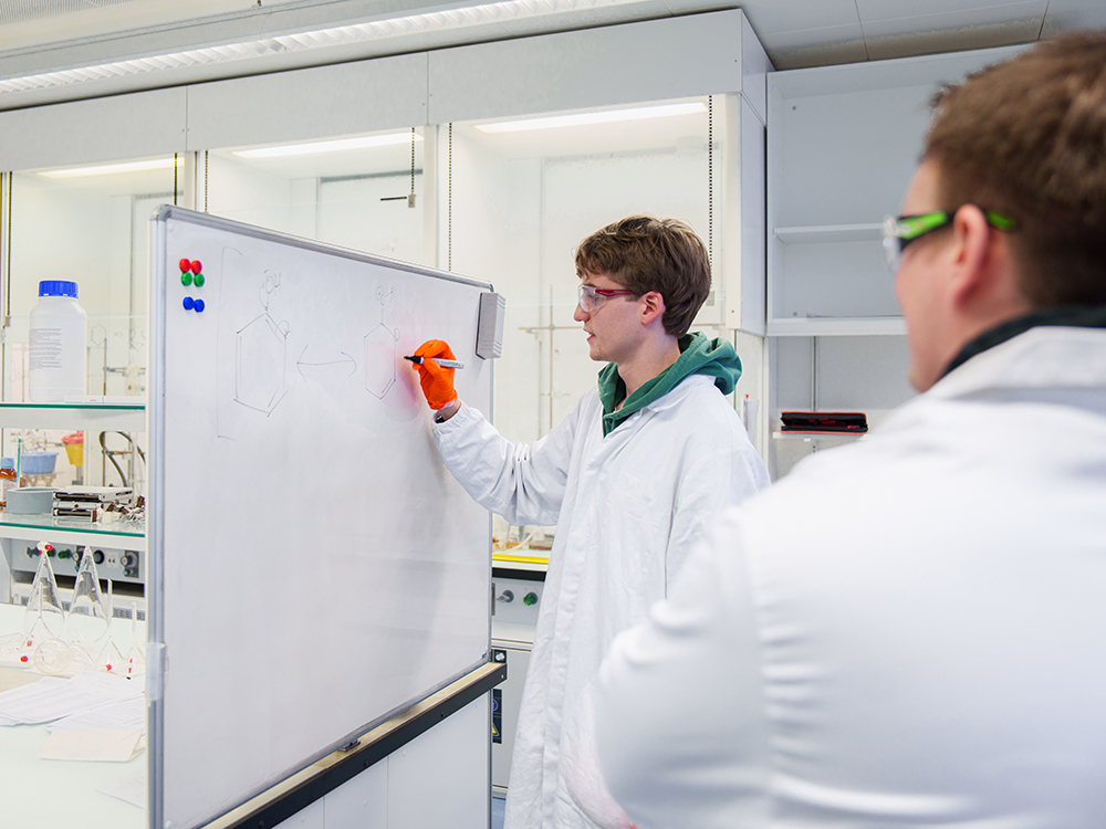 Ein Student notiert etwas auf eine weisse Tafel, während ihm ein Doktorand über die Schulter schaut. Ein Student notiert etwas auf eine weisse Tafel, während ihm ein Doktorand über die Schulter schaut.