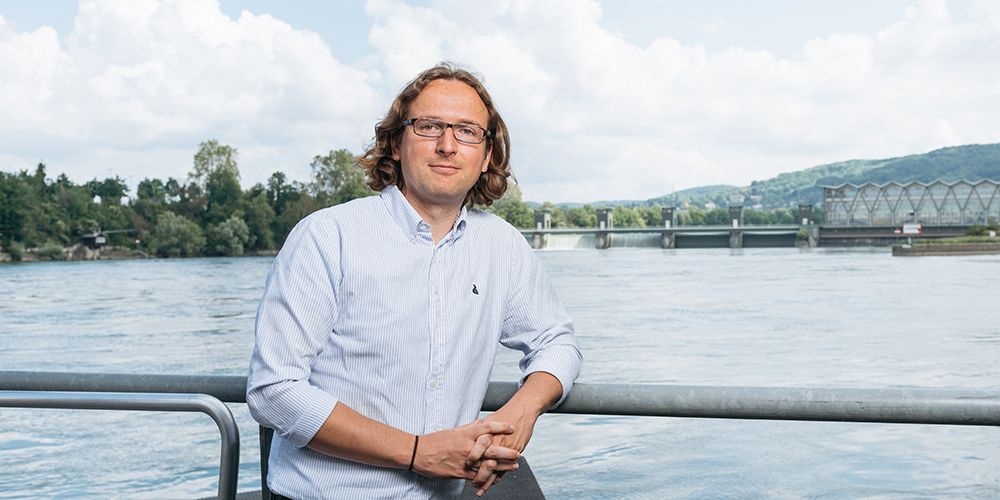 Prof. Dr. Hannes Weigt vor dem Kraftwerk Birsfelden (Bild: Universität Basel, Oliver Hochstrasser).