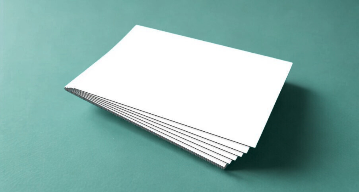 Ein Foto zeigt einen Stapel Broschüren auf einen blaugrauen Untergrund.