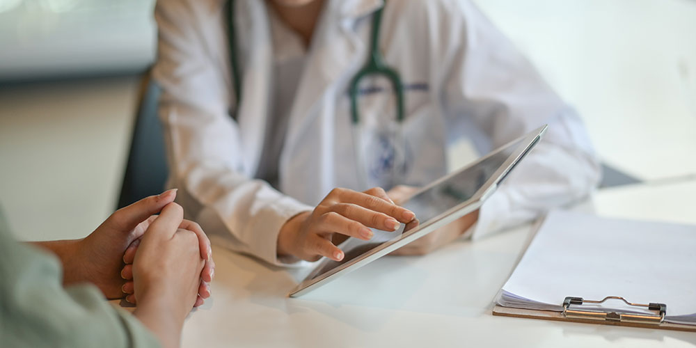 Medizinisches Personal zeigt einem Patienten ein Tablet mit Informationen