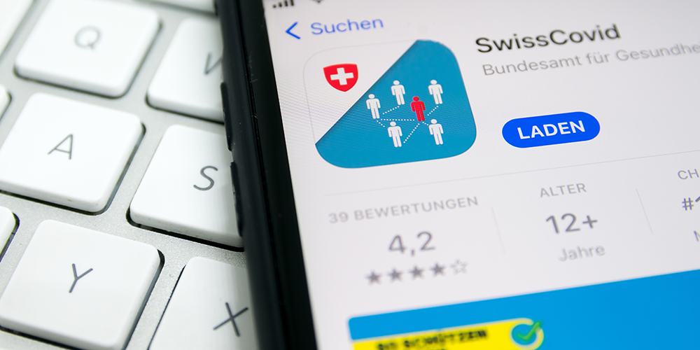 Smartphone screen shows the SwissCovid app. 