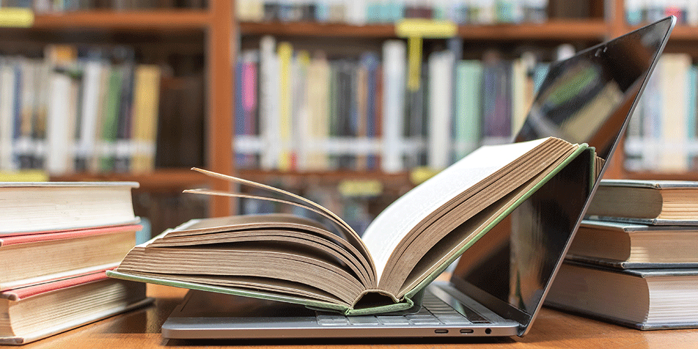Aufgeschlagenes Buch auf Laptop Aufgeschlagenes Buch auf Laptop
