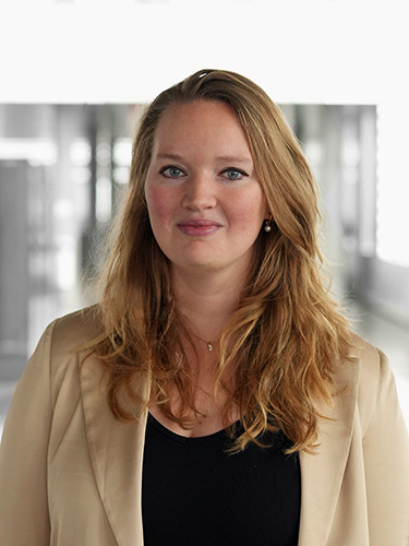 Porträt einer Frau mit langen rötlich-blonden Haaren, beigem Blazer und schwarzem Oberteil vor einem unscharfen Hintergrund. Porträt einer Frau mit langen rötlich-blonden Haaren, beigem Blazer und schwarzem Oberteil vor einem unscharfen Hintergrund.